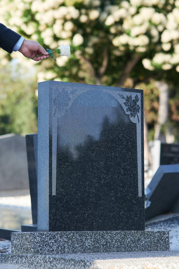 The final goodbye. Cropped shot of a man placing a white rose on a grave.